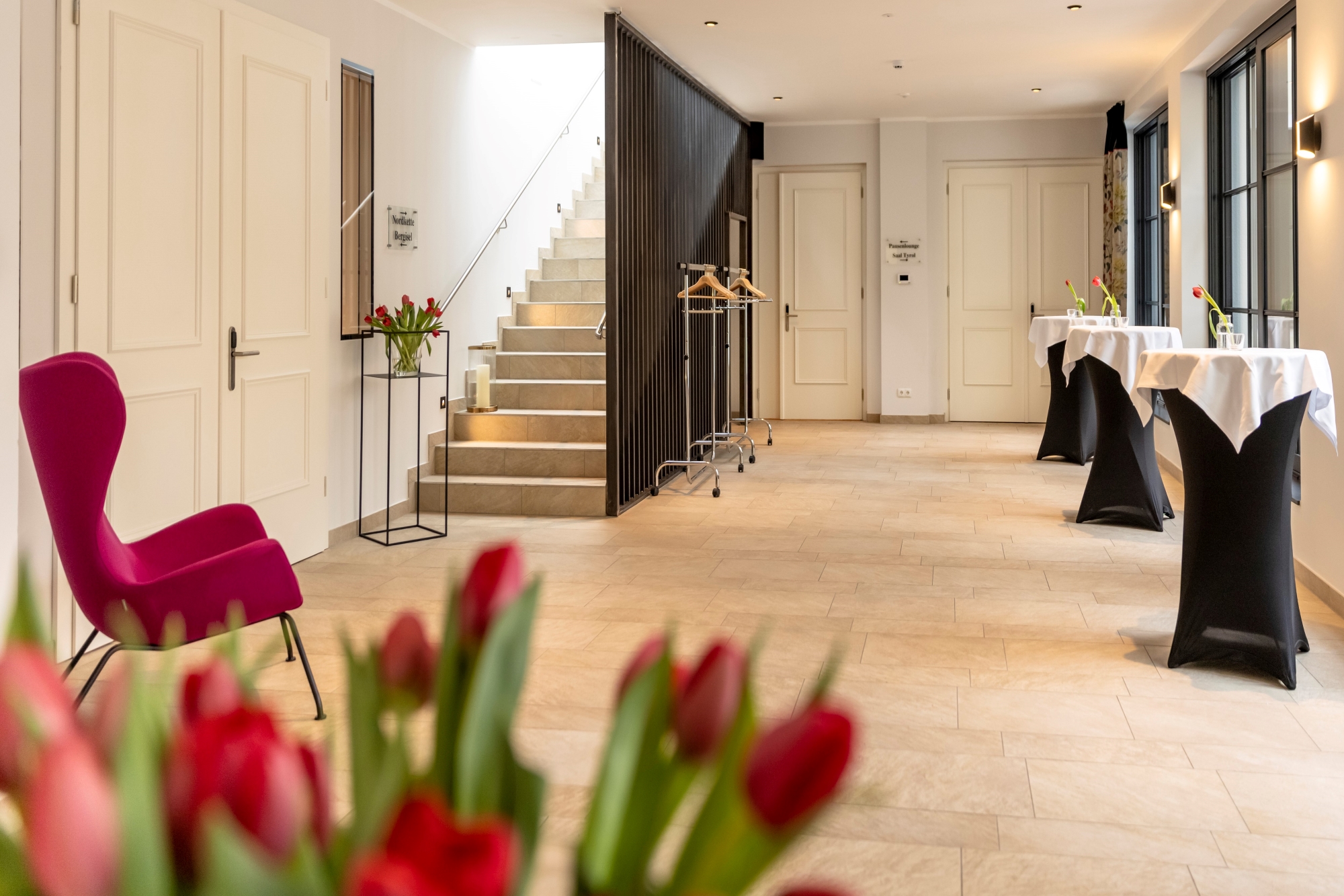 Ingresso elegante con tulipani rossi e ambiente invitante, scale chiare sullo sfondo.